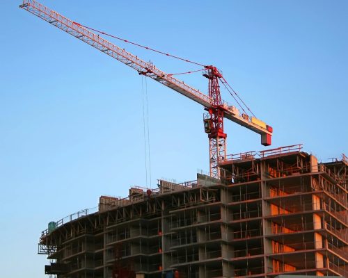 Tower crane on a high-rise building under construction at sunset, showcasing modern urban development.